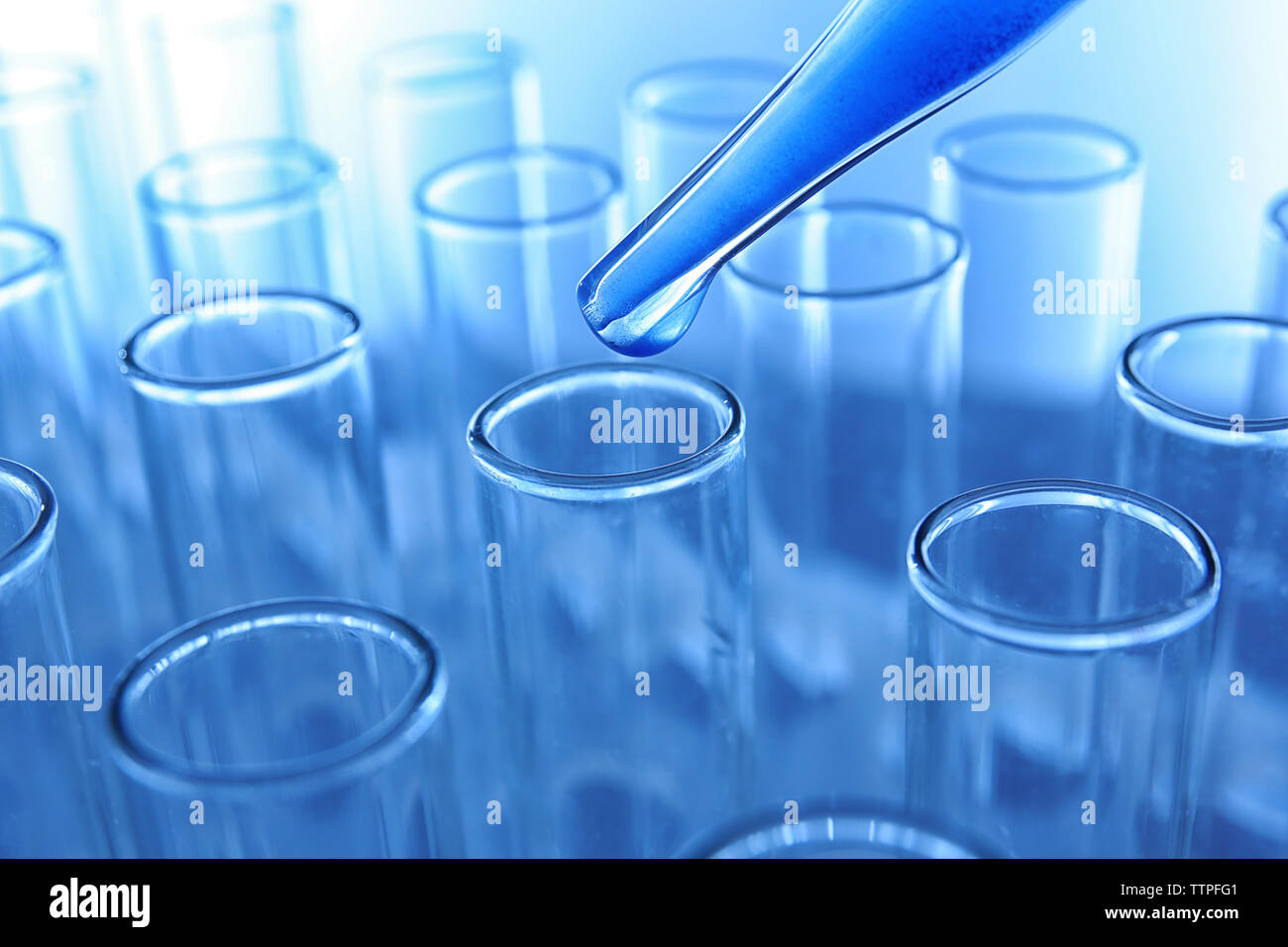 Nahaufnahme von einer Pipette Fallenlassen einer blauen Probe in ein Reagenzglas Stockfoto