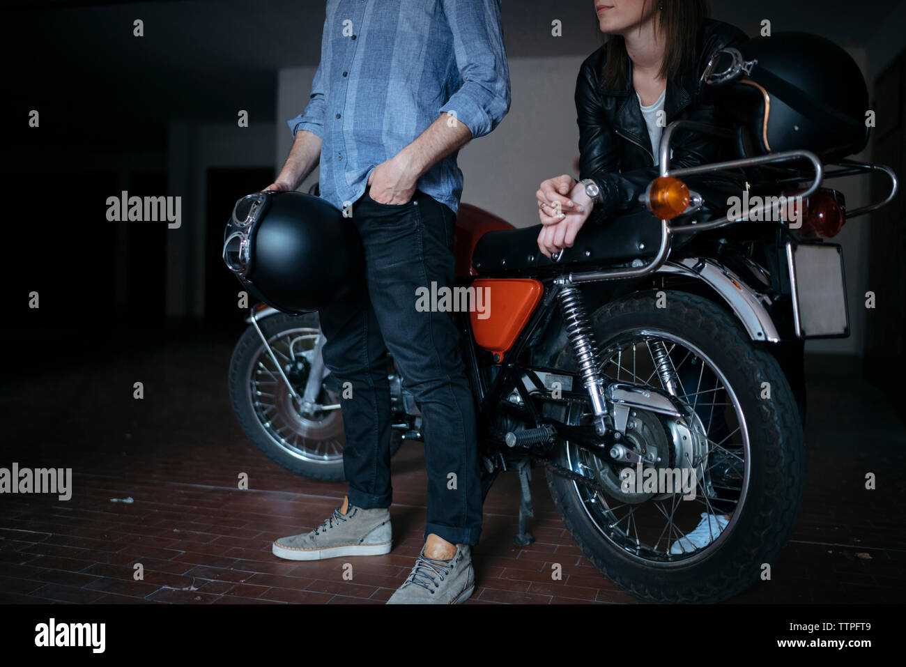Untere Partie des jungen Paares steht mit dem Motorrad in der Werkstatt Stockfoto