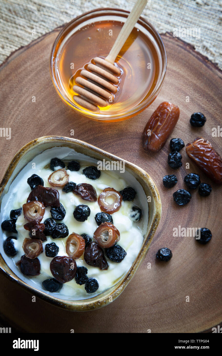 Ansicht von oben der getrockneten Früchte im Joghurt mit Honig auf Tisch Stockfoto