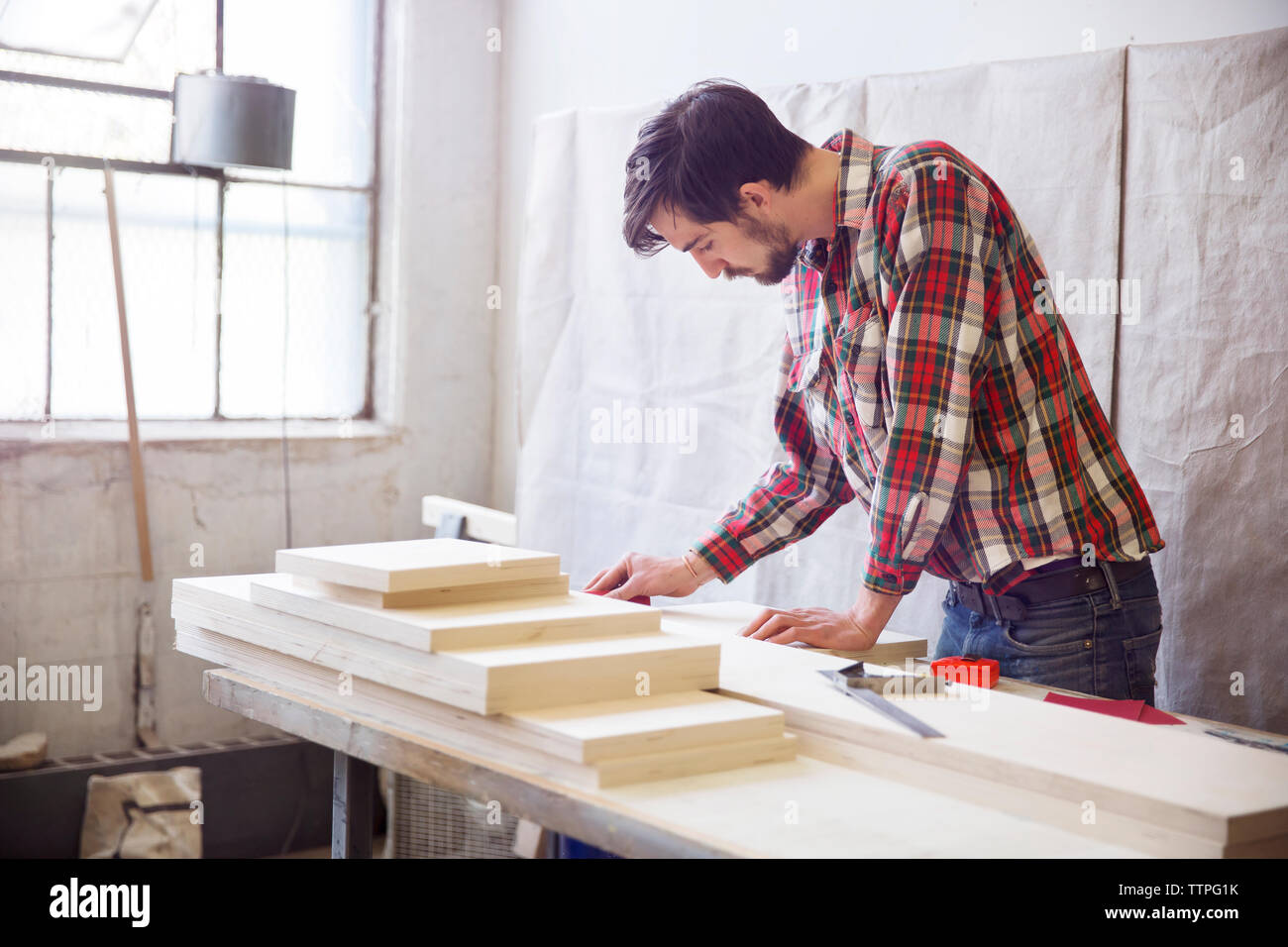 Mann an der hölzernen Planken in der Werkstatt suchen Stockfoto