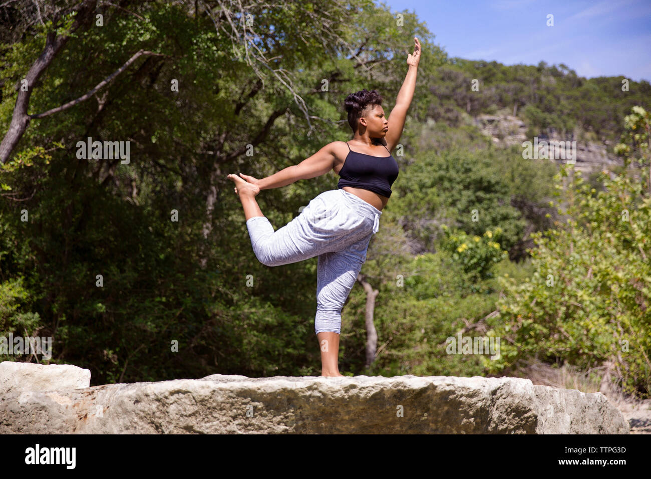 Low Angle View von Frau stretching beim Üben von Yoga im Wald Stockfoto