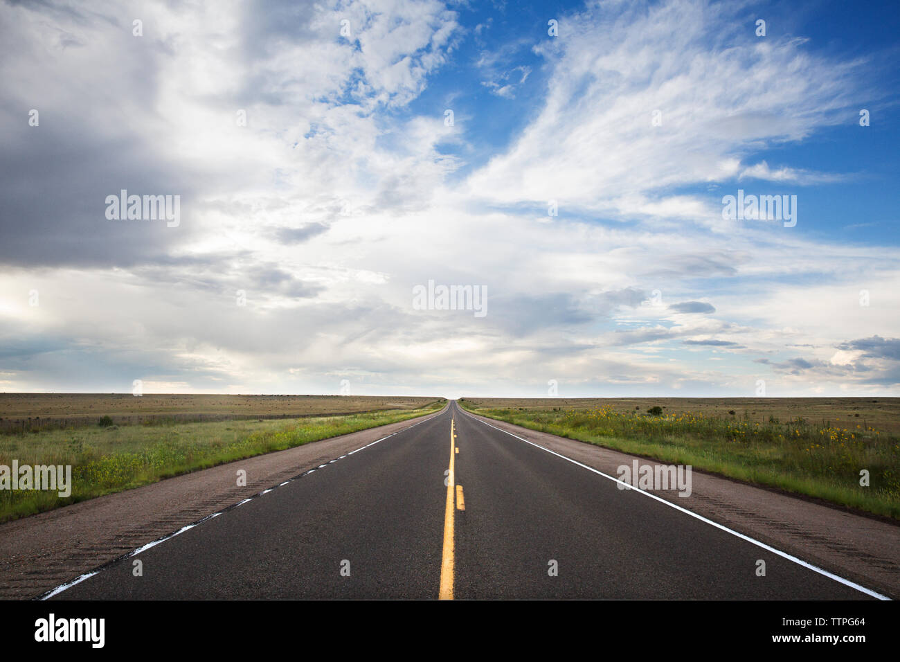 Landstraße inmitten Feld gegen bewölktem Himmel Stockfoto