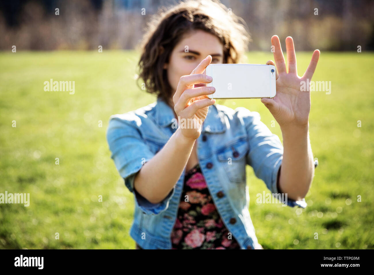 Frau Fotografieren durch Smart Phone auf Wiese Stockfoto