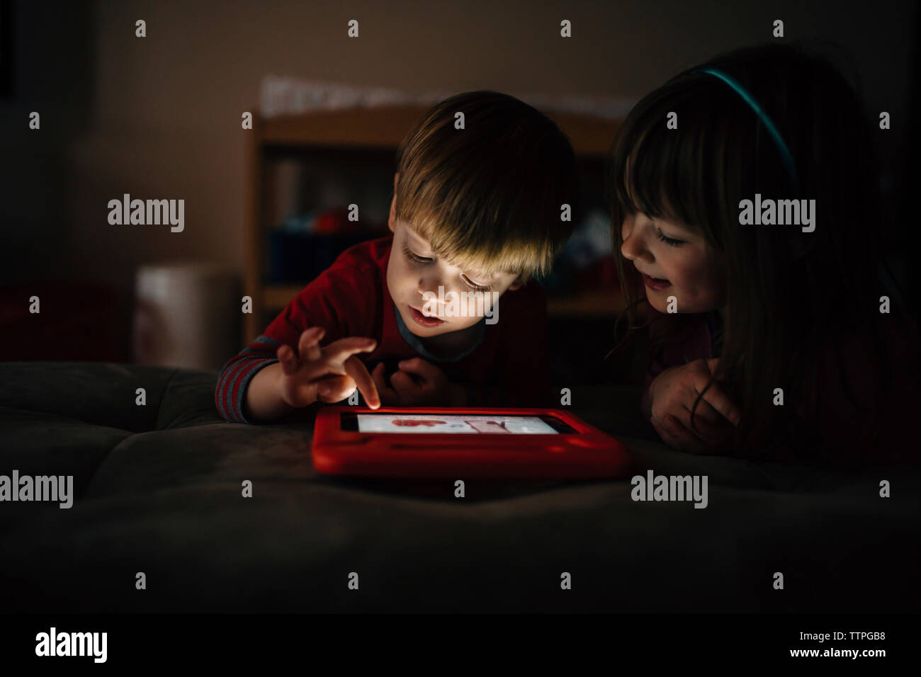 Gerne Geschwister spielen video Spiel, während am Bett zu Hause liegen Stockfoto