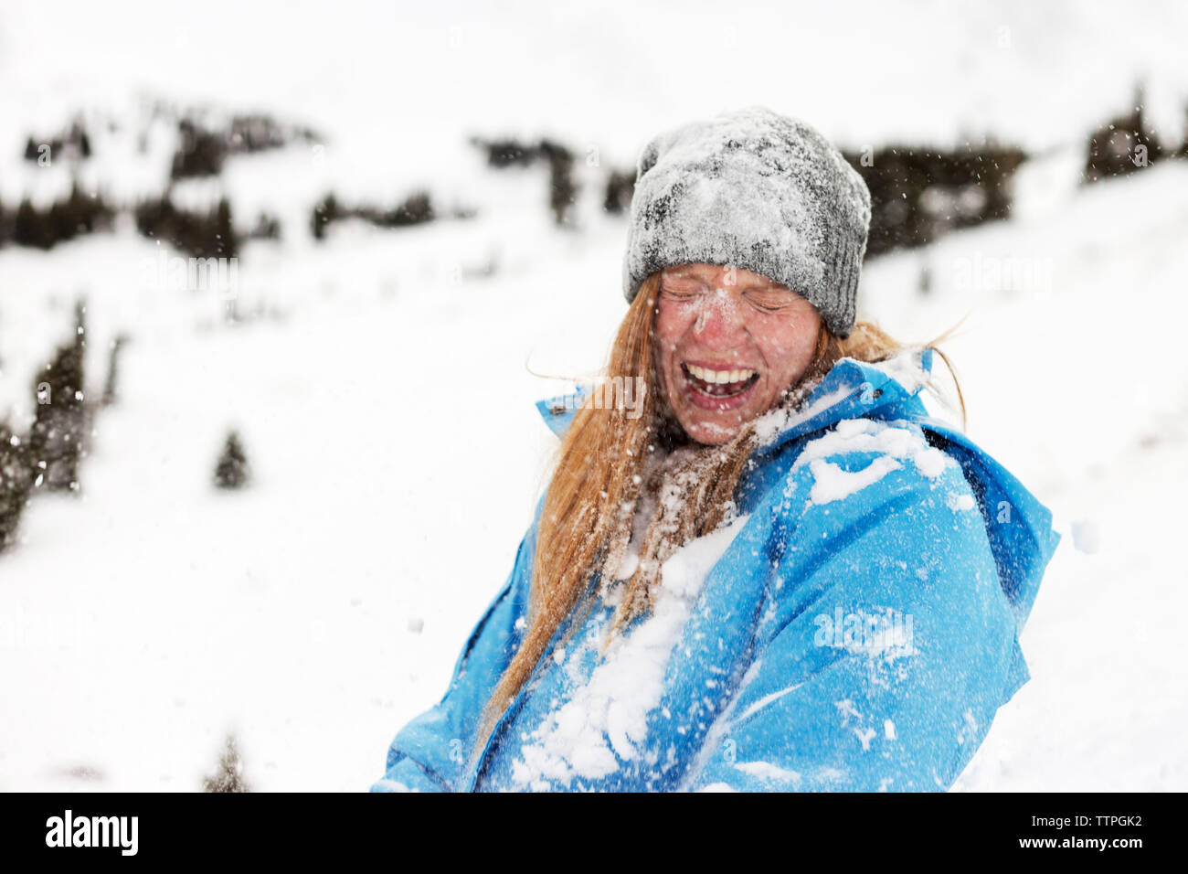 Fröhliche Frau mit Schnee bedeckt Stockfoto