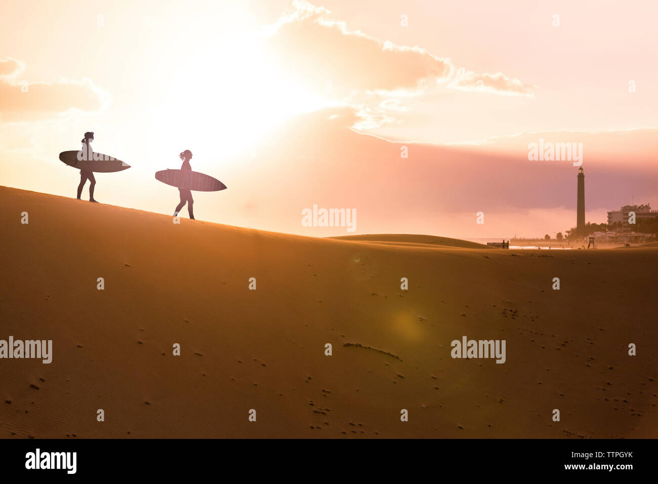 Silhouette Freunde mit Surfboards Wandern in der Wüste bei Sonnenuntergang Stockfoto
