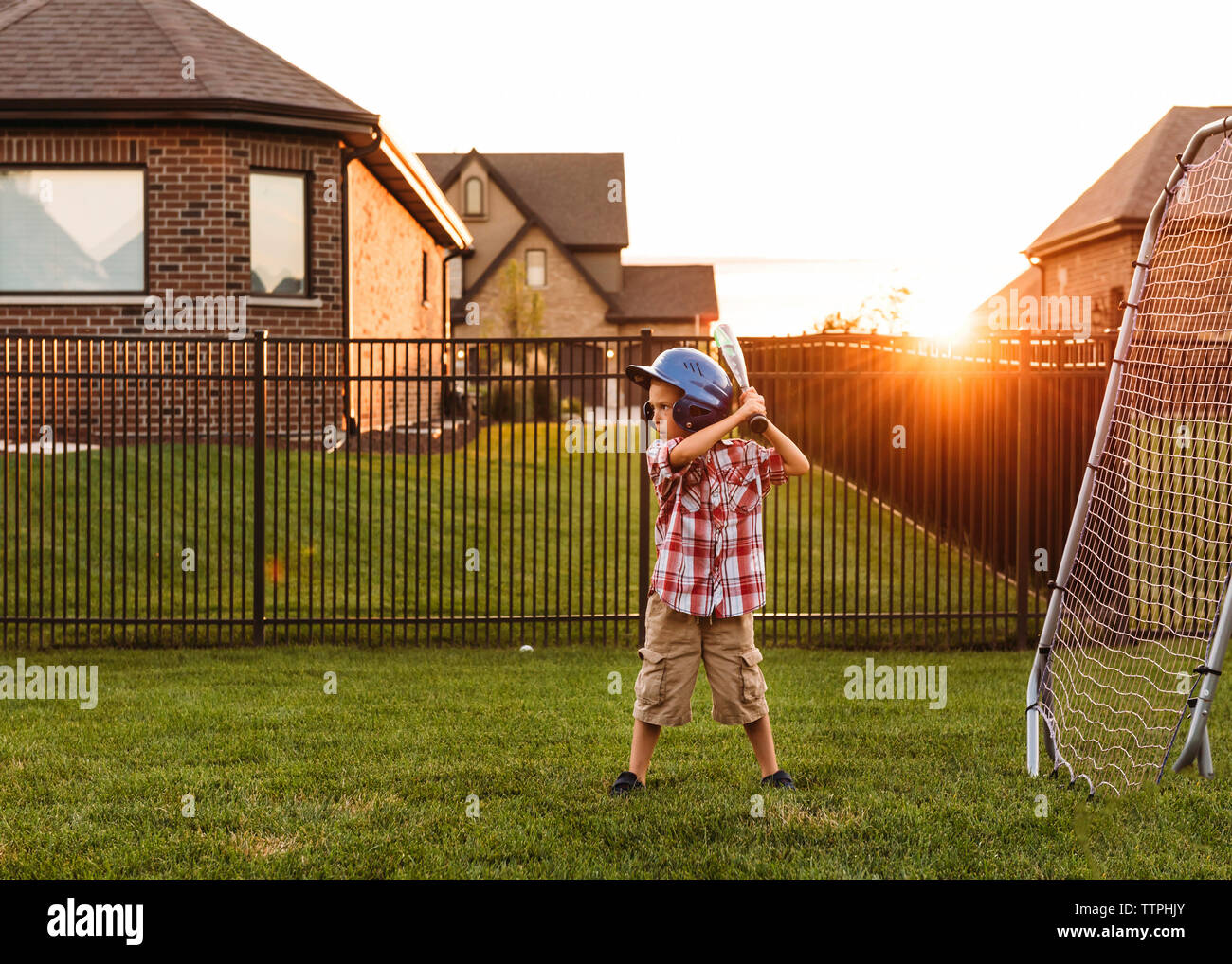 Junge spielt Baseball im Hinterhof bei Sonnenuntergang Stockfoto