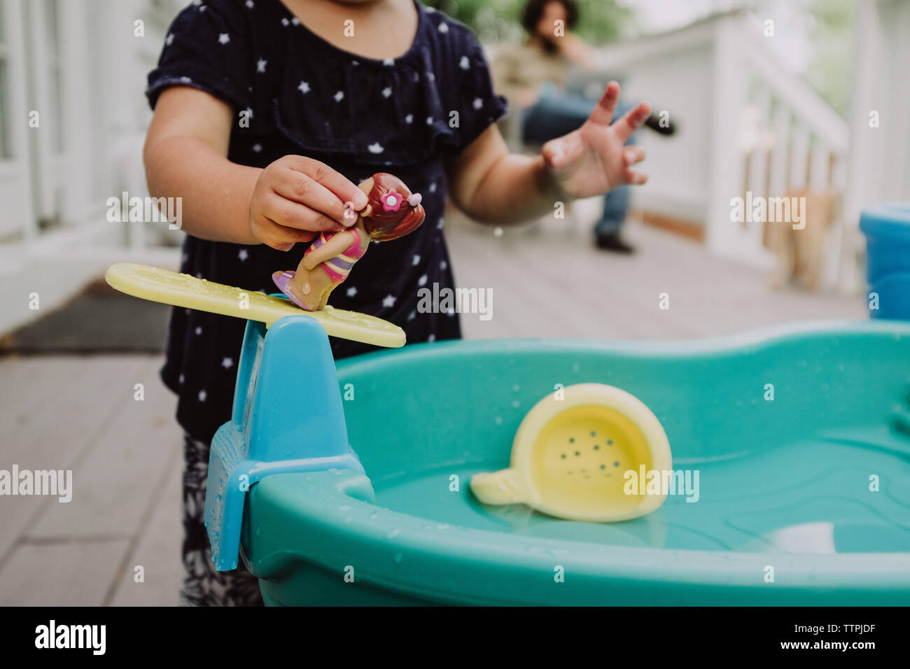 Mädchen spielen mit Wasser Spielzeug, während Papa arbeitet im Hintergrund Stockfoto