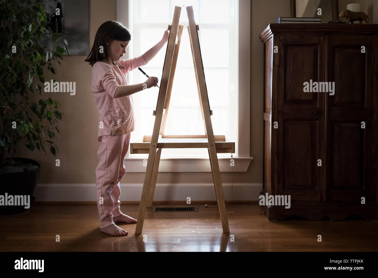 Seitenansicht des Mädchens Zeichnung auf Künstlerleinwand während zu Hause stehend Stockfoto