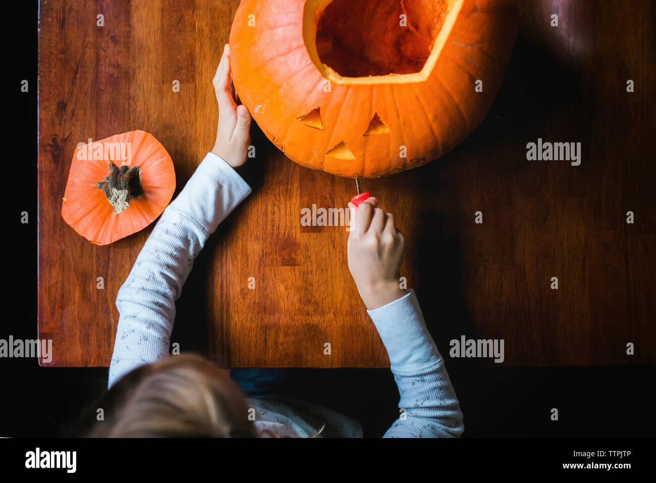 Ansicht von oben von Mädchen schneiden Kürbis Stockfoto