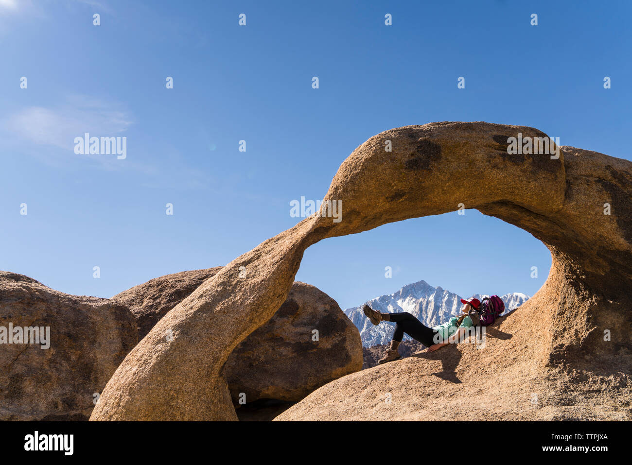 Weibliche Wanderer liegen auf Rock Formation gegen den blauen Himmel Stockfoto