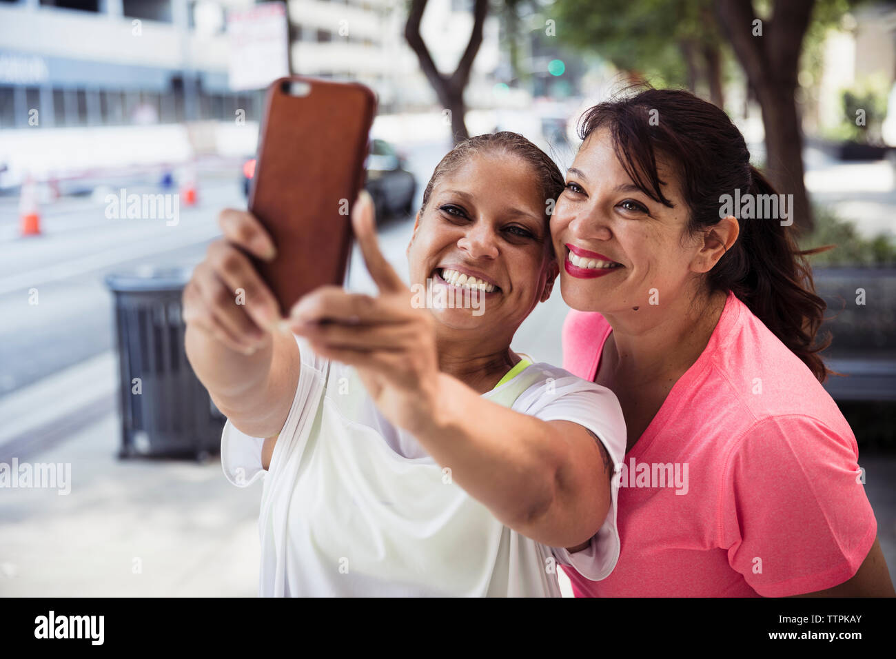Freundliche weibliche Freunde unter selfie mit Smart Phone auf Fußweg Stockfoto