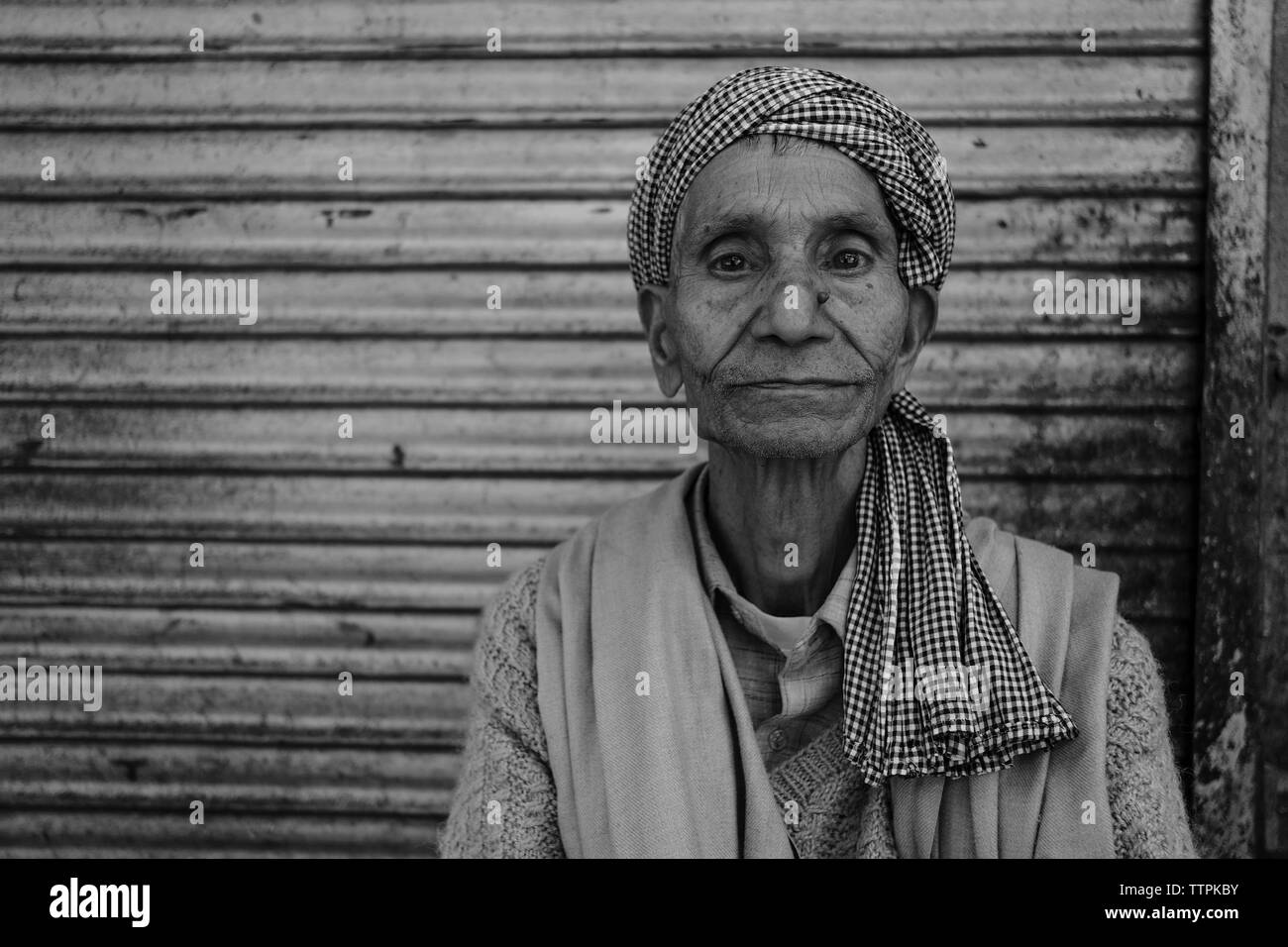 Portrait von älteren Mann mit Turban sitzen gegen geschlossene Blende in der Stadt Stockfoto