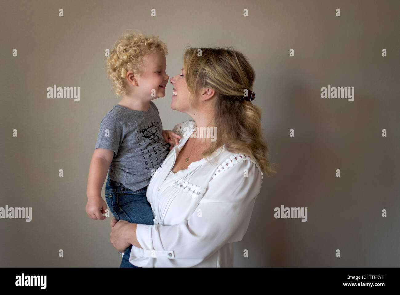 Fröhliche Mutter mit Sohn gegen die Wand zu Hause Stockfoto