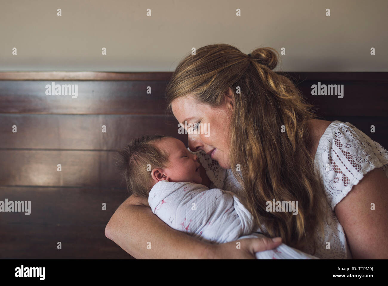 Liebevolle Mutter tragen Schlafen neugeborene Tochter zu Hause Stockfoto