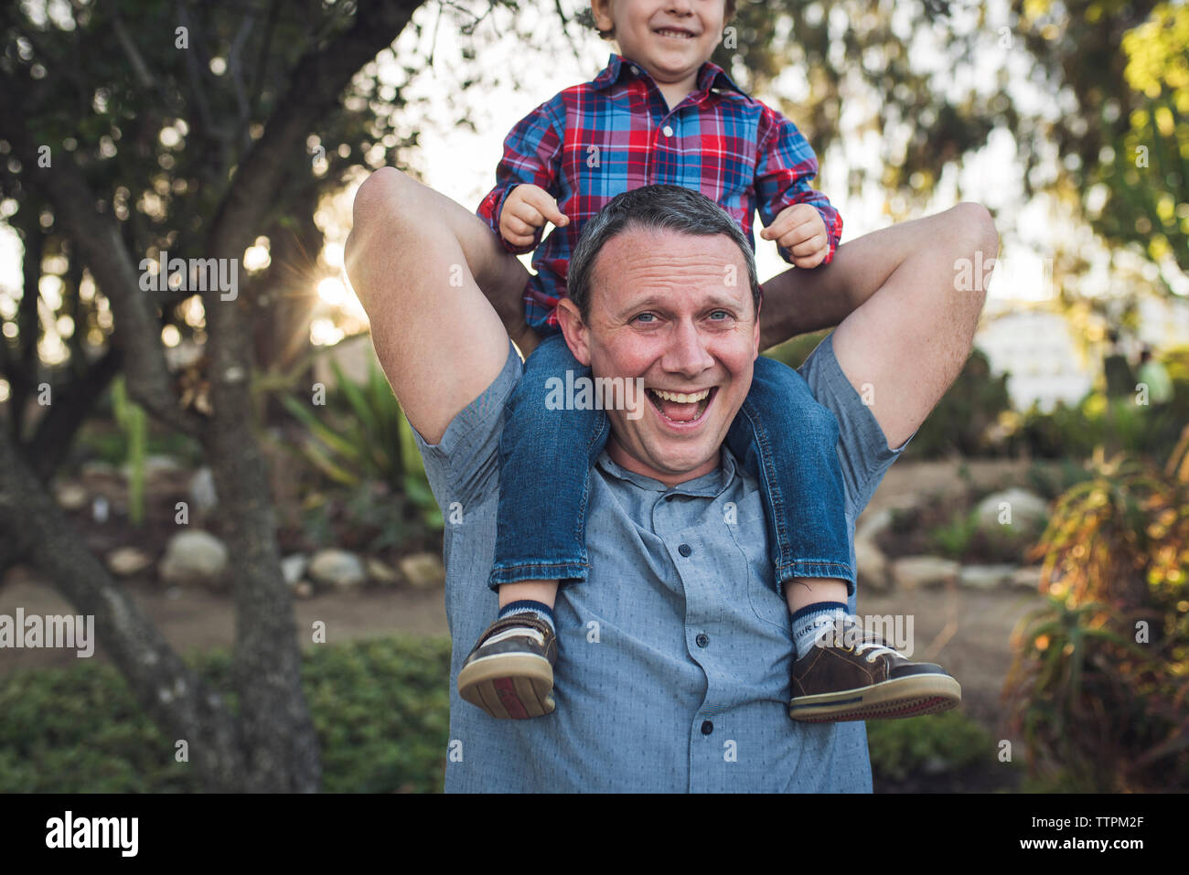 Portrait von fröhlichen Vater mit Sohn auf Schultern, während Sie mit ihm im Park Stockfoto