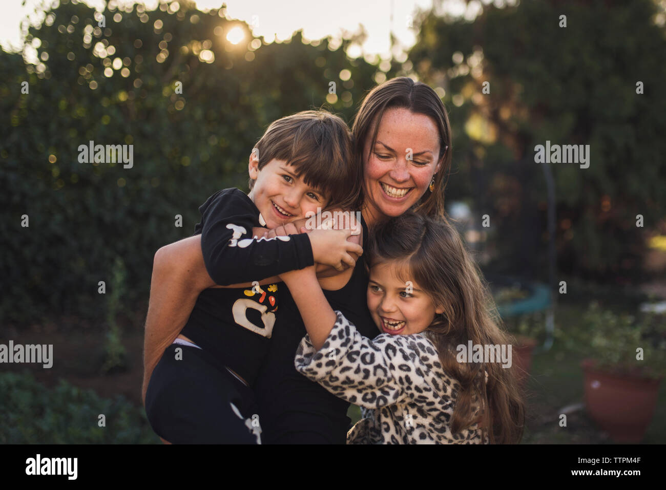 Glückliche Mutter spielt mit den Kindern im Hof bei Sonnenuntergang Stockfoto