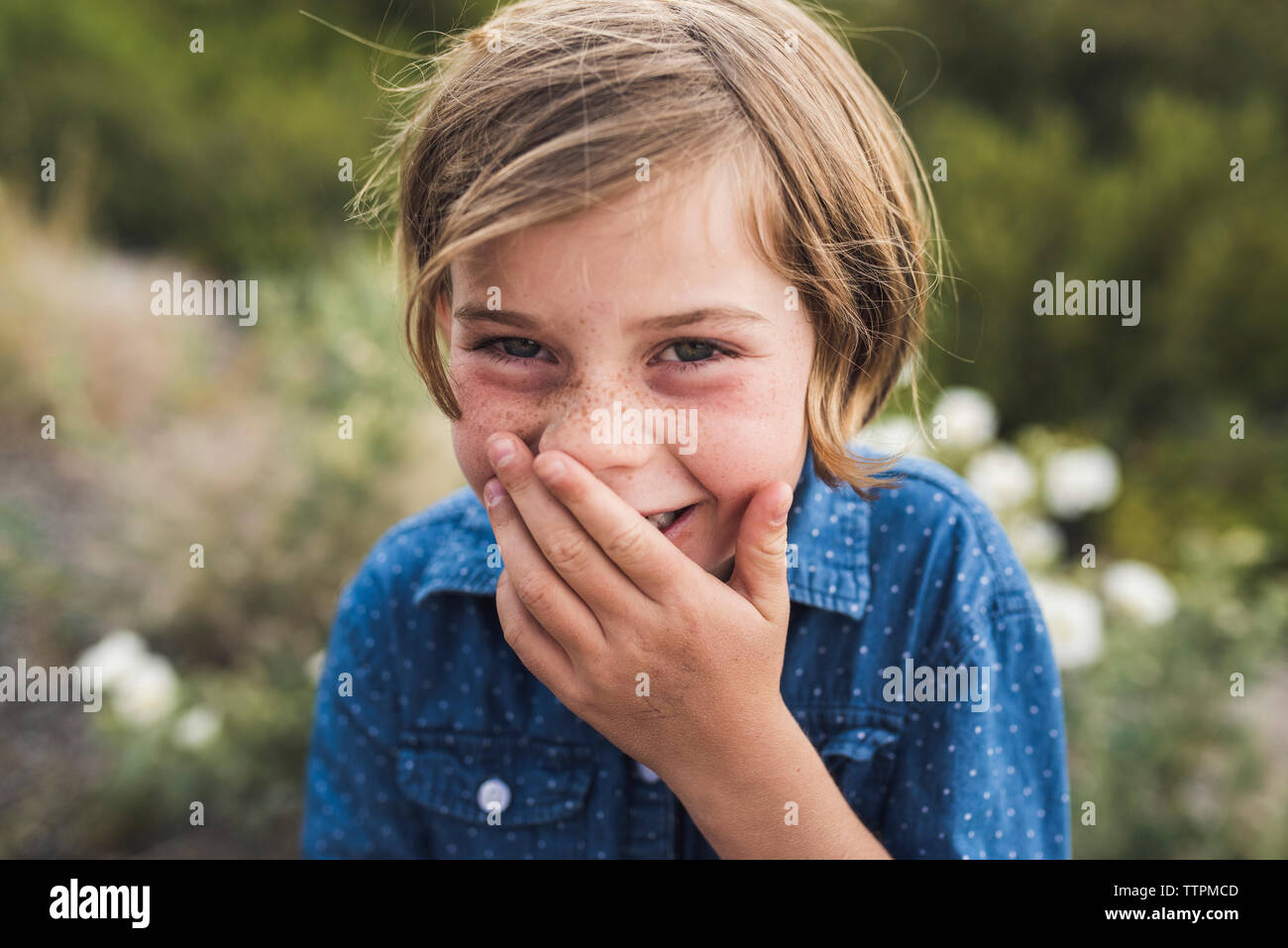 Close-up Portrait von glücklichen Mädchen mit der Hand in den Mund im Wald Stockfoto