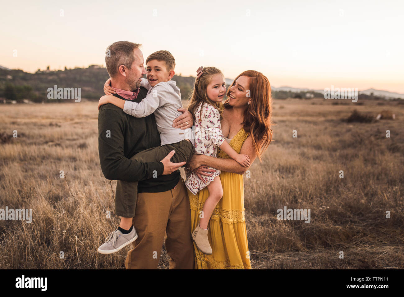 Jungen und Mädchen, die von den Eltern in Kalifornien statt bei Sonnenuntergang Stockfoto