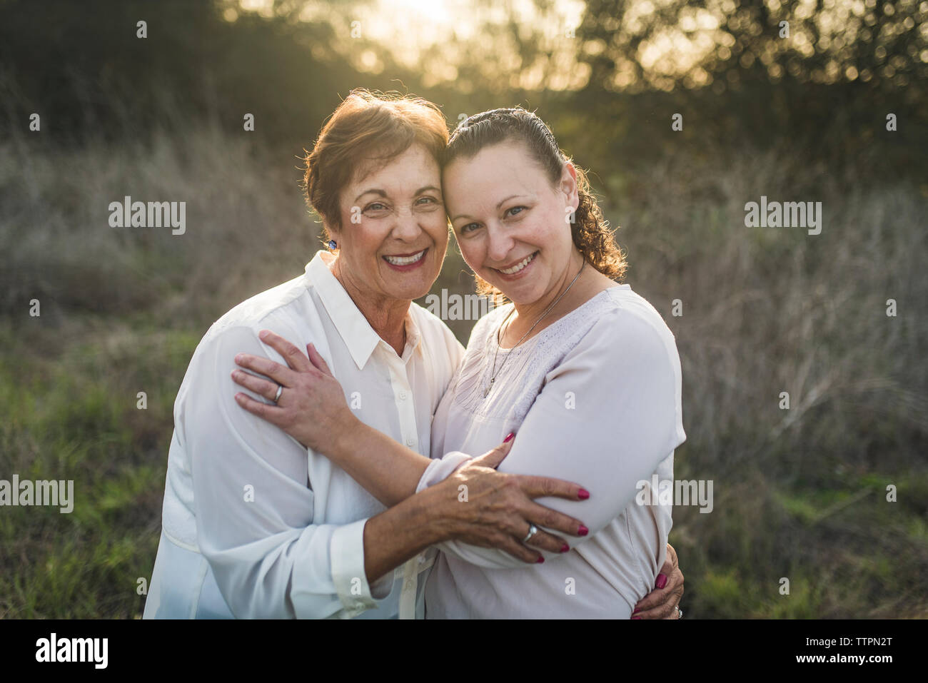Portrait von Erwachsenen Mutter und Tochter umarmen und lächelnd an Kamera Stockfoto