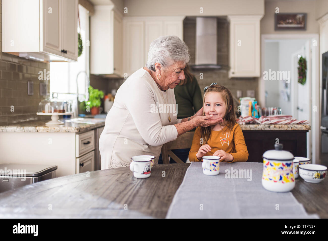 Enkelin und Urgroßmutter am Küchentisch Stockfoto