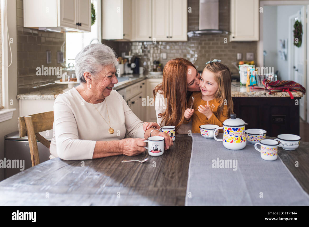 Mehr-generationen-Familie spielen mit Kaffee am Küchentisch gesetzt Stockfoto