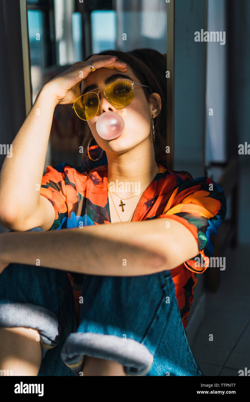 Junge Frau mit dem Kopf in der Hand blasen Bubble Gum zu Hause Stockfoto