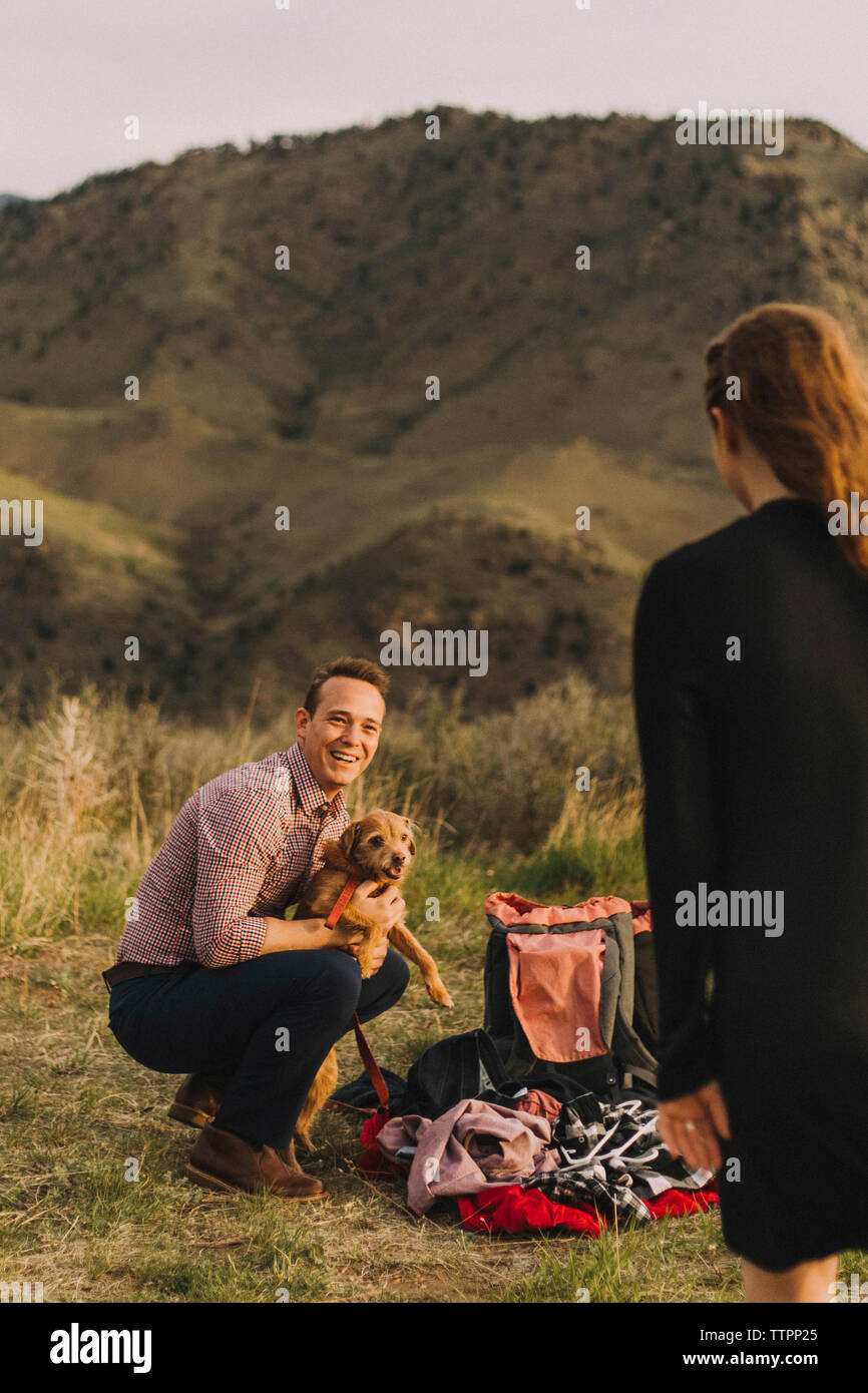 Freund der Hund während Sie Freundin auf Feld gegen Berge Stockfoto