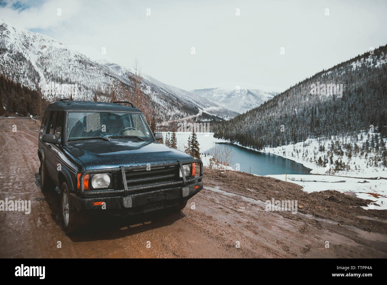 Off-road-Fahrzeug auf nasser Piste gegen bewölkter Himmel im Winter Stockfoto