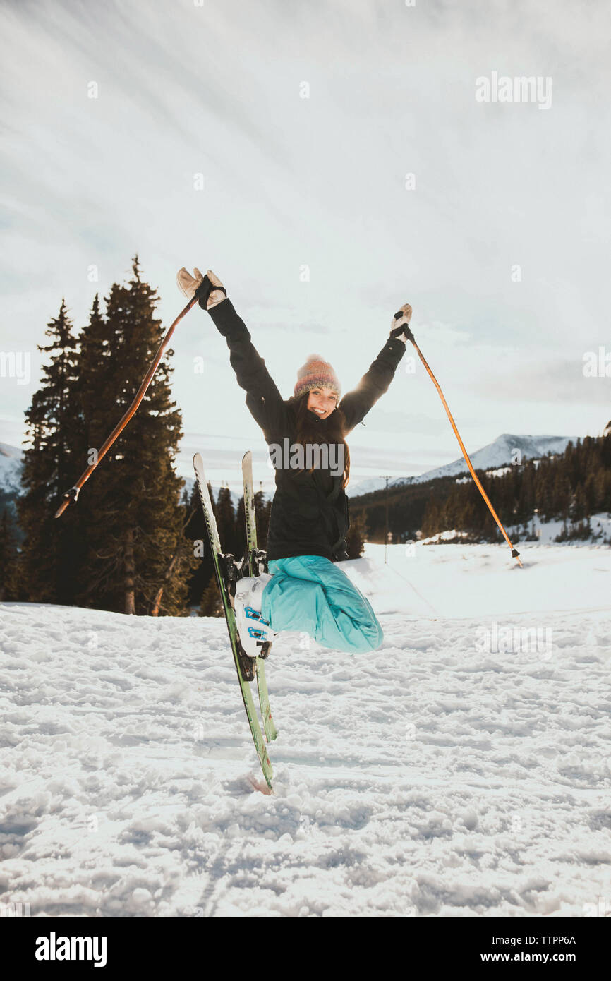 Junge Frau springen beim Skifahren auf verschneiten Feld aufgeregt Stockfoto