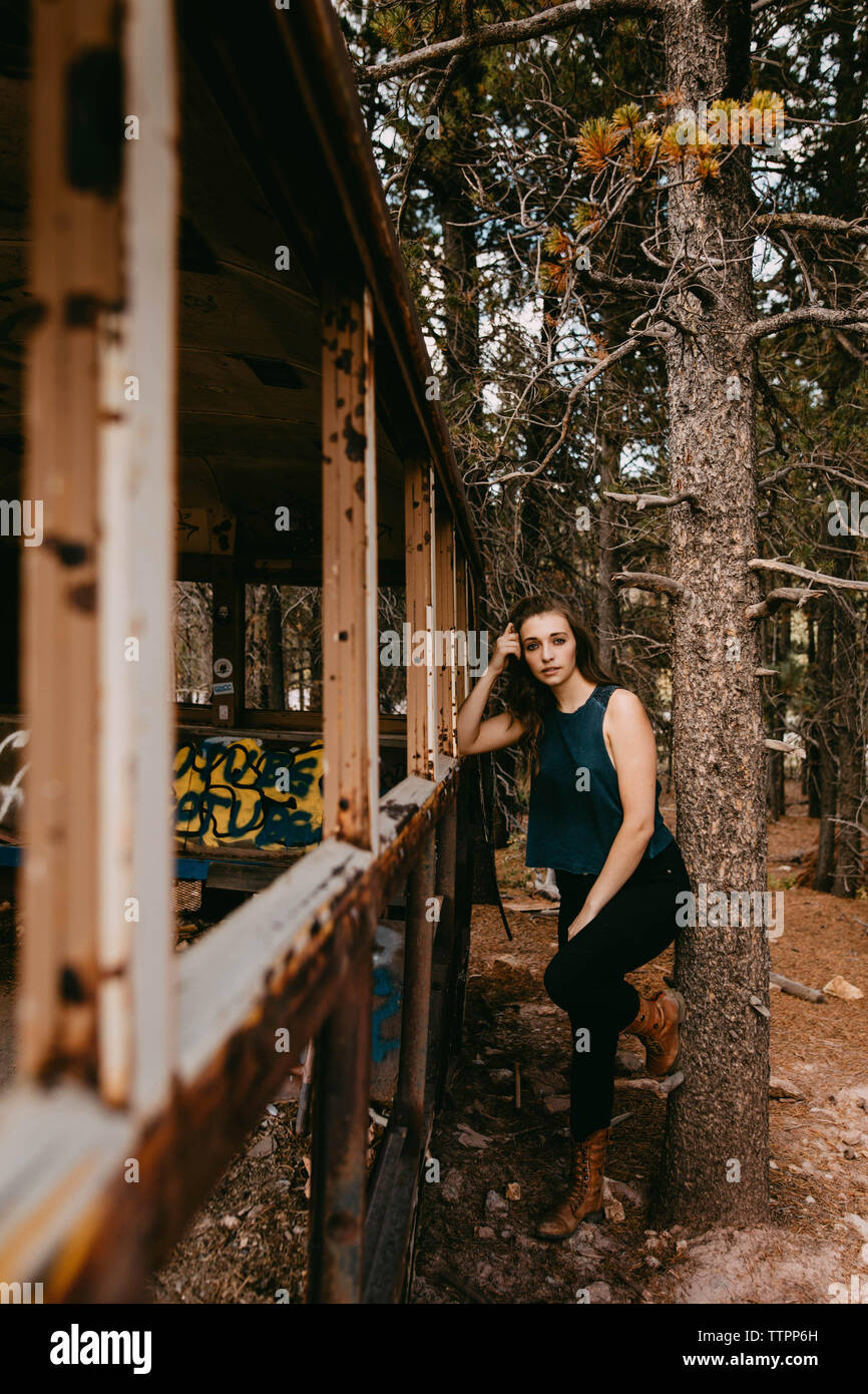 Portrait von selbstbewussten jungen Frau, die durch verlassene Fahrzeug im Wald Stockfoto