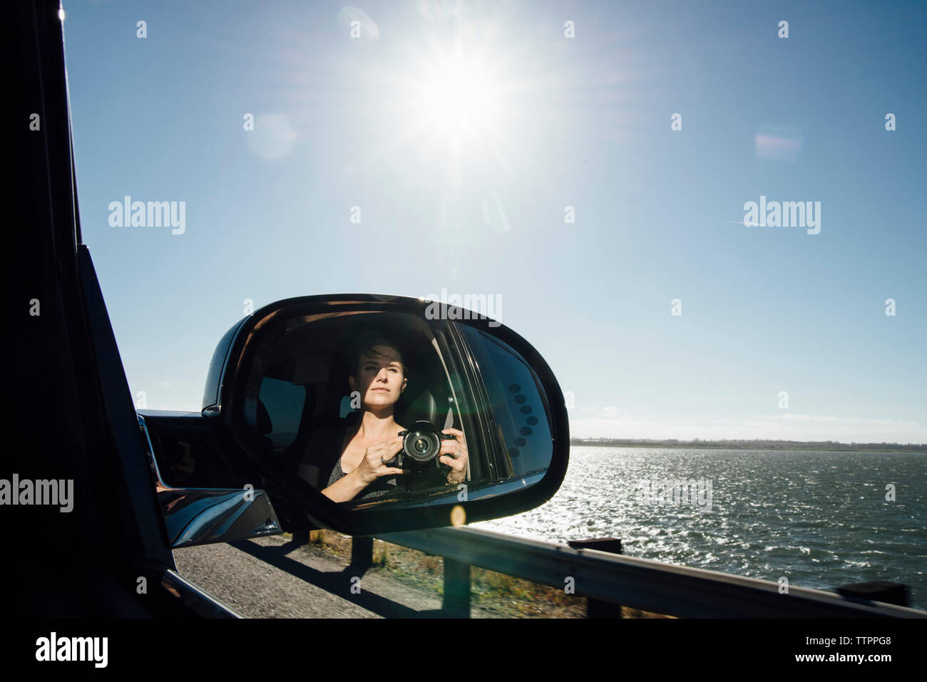 Frau fotografieren, während auf die Außenspiegel des Autos gegen Sky Stockfoto