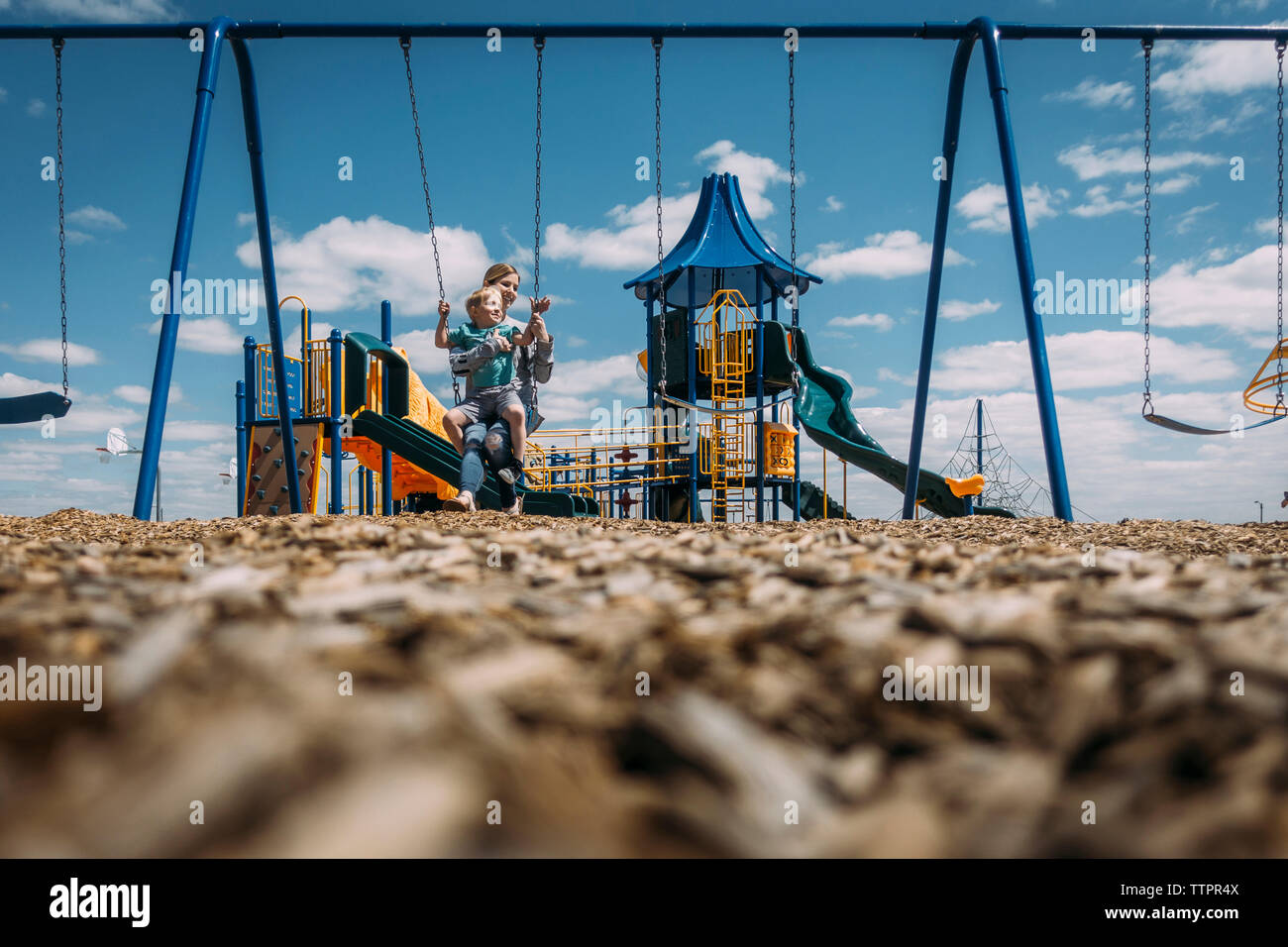 Mutter und Sohn auf Swing im Park sitzen gegen Sky Stockfoto