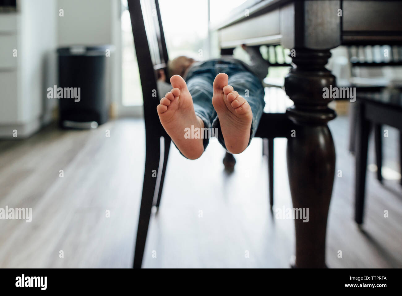 Niedrige Abschnitt von baby boy liegen auf Stuhl von Tisch zu Hause Stockfoto