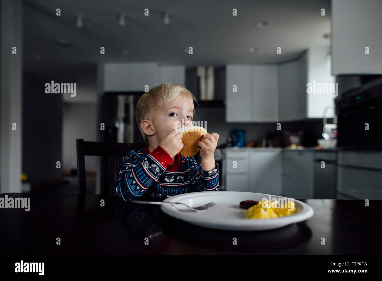 Portrait von baby boy Essen, während Sie von Esstisch zu Hause sitzen Stockfoto