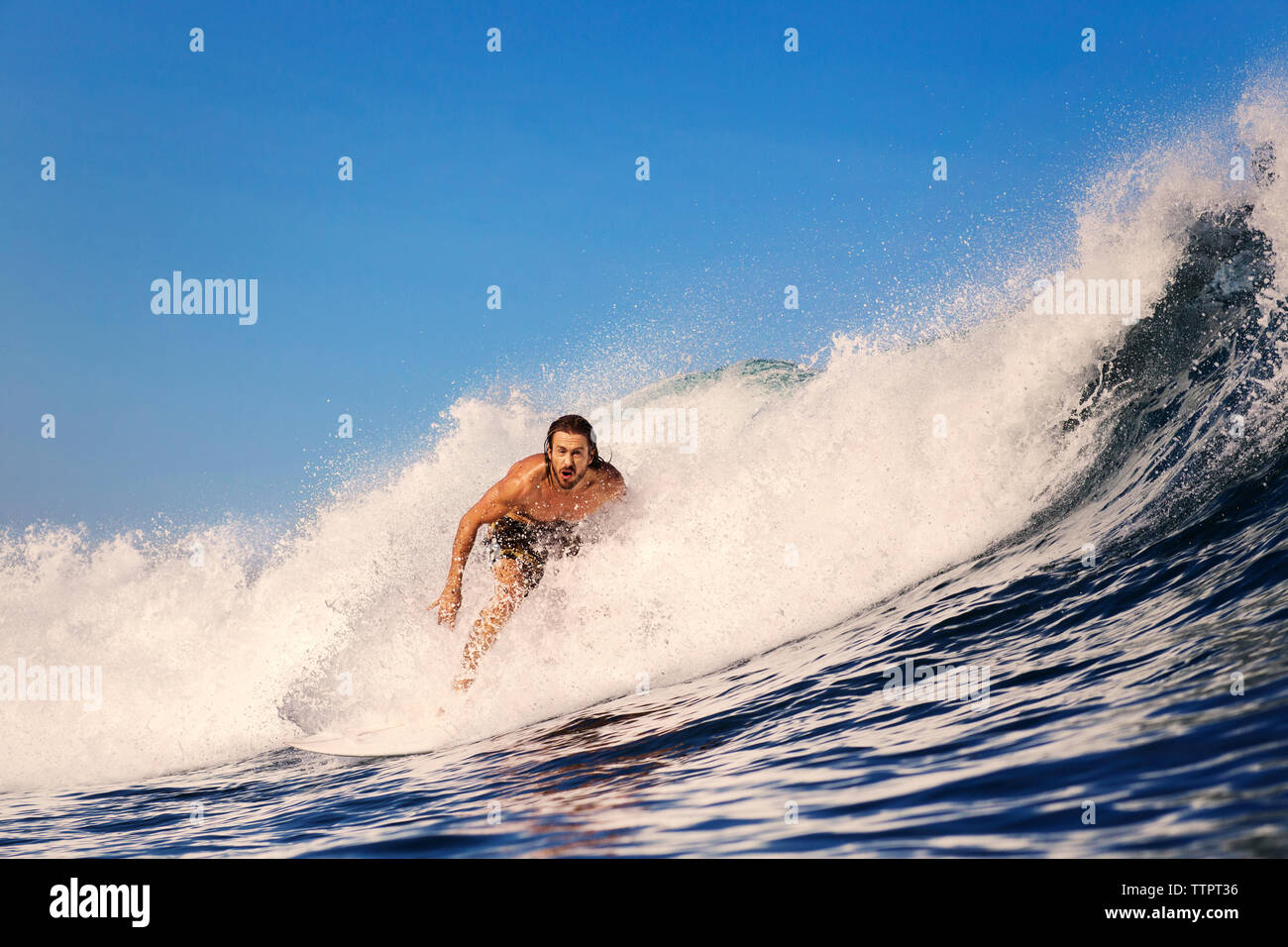 Mitte der erwachsene Mann Surfen im Meer gegen blauen Himmel Stockfoto