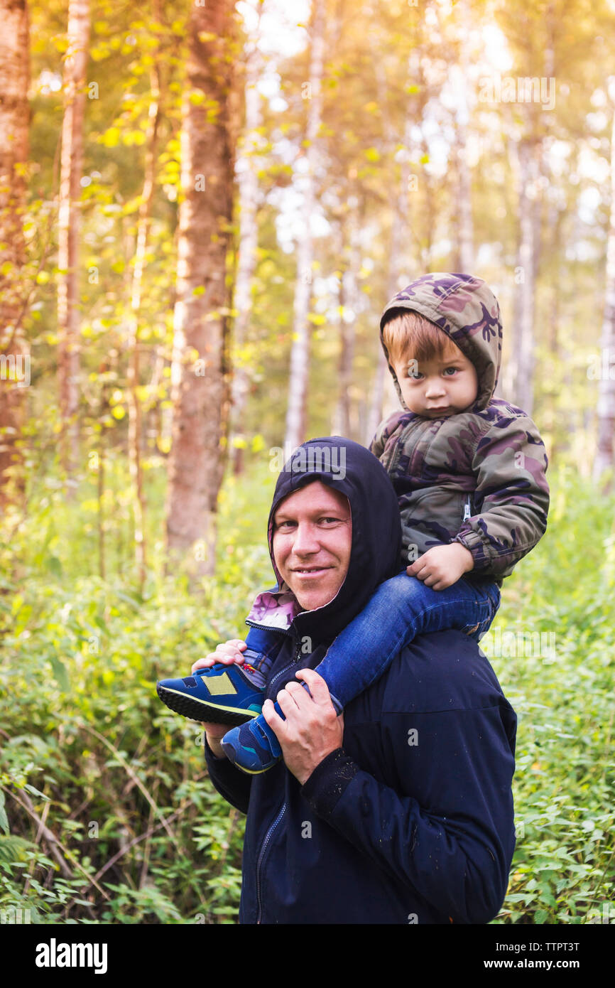 Porträt der glückliche Vater mit Sohn auf den Schultern im Wald Stockfoto