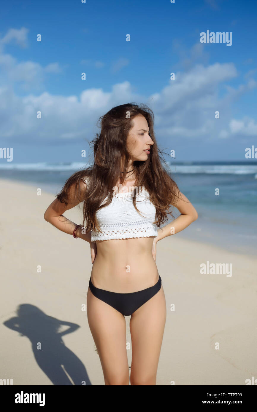 Nachdenkliche Frau mit Händen auf den Hüften am Strand stehen Stockfoto