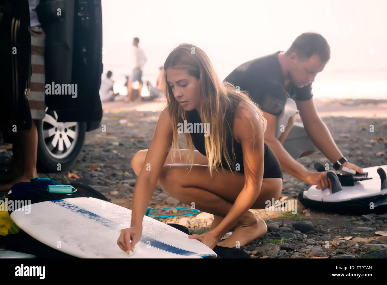 Freunde mit Surfboards zusammengekauert am Strand gegen Sky Stockfoto