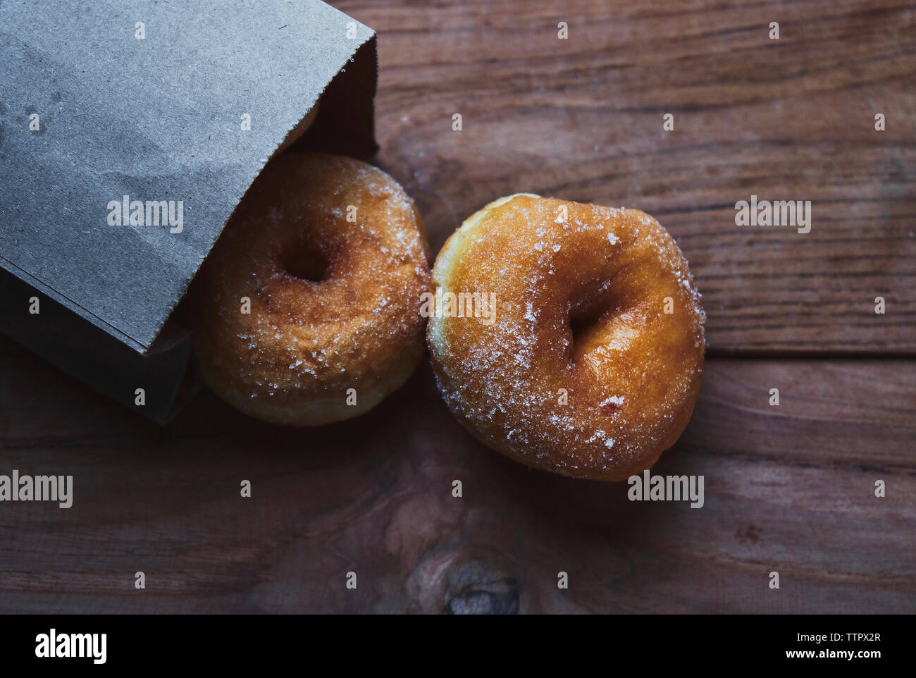 Hohe Betrachtungswinkel der Krapfen mit papiertüte auf Tisch Stockfoto