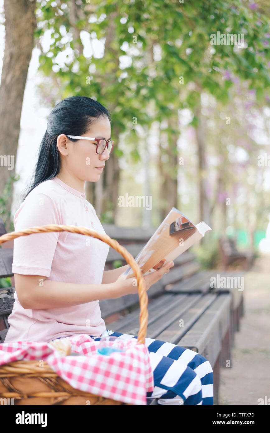 Frau mit Buch beim Sitzen auf der Bank im Park Stockfoto