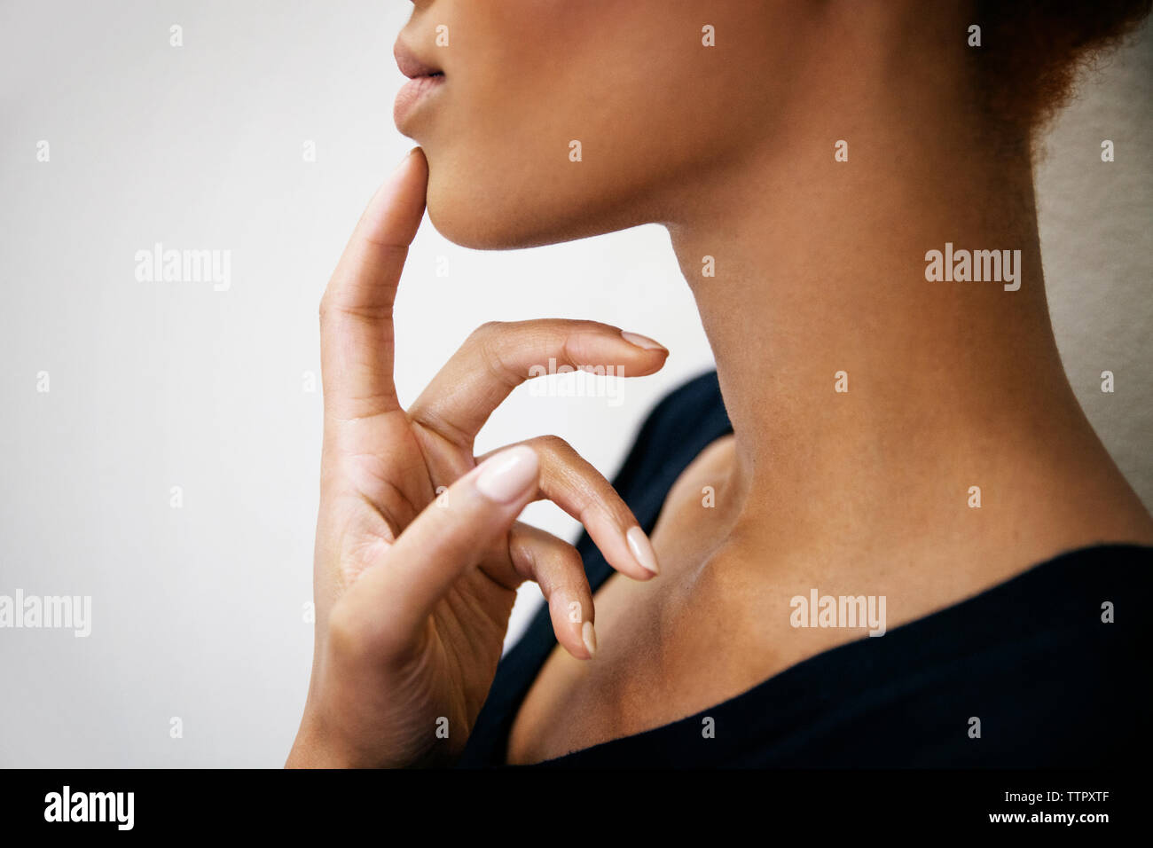 Seitenansicht der Mittelteil der Frau mit dem Finger auf das Kinn Stockfoto