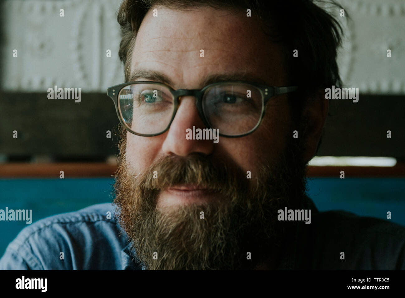 Close-up von nachdenklich Mann mit Bart tragen Brillen, während zu Hause sitzen Stockfoto