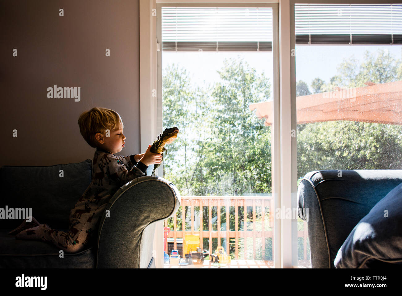 Jungen spielen mit Spielzeug, während kniend auf Sessel zu Hause Stockfoto