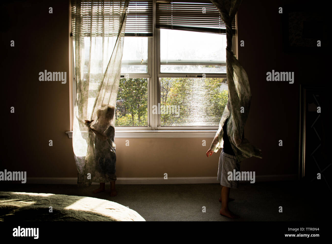 Kinder spielen mit Vorhängen zu Hause Stockfoto