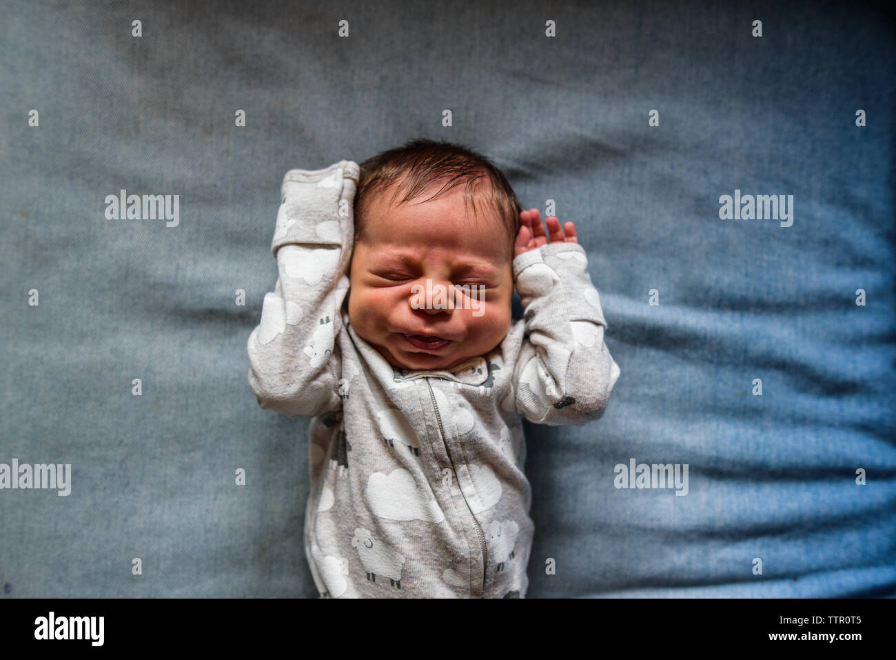 Neugeborene zur Festlegung und lustiges Gesicht mit den Händen bis Stockfoto