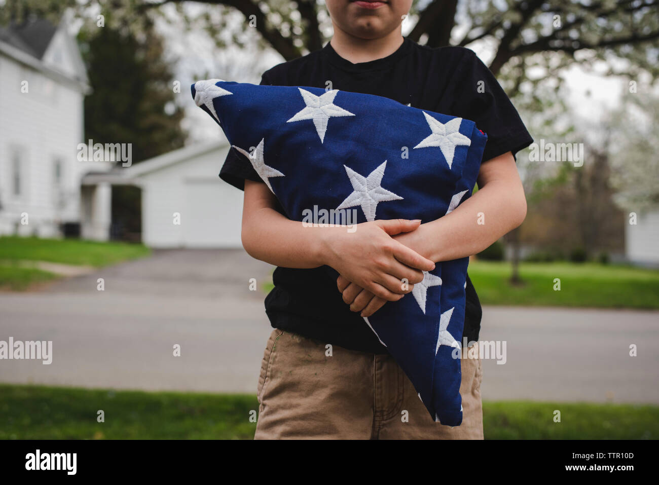 Mittelteil der boy Holding amerikanische Flagge beim Stehen im Park Stockfoto