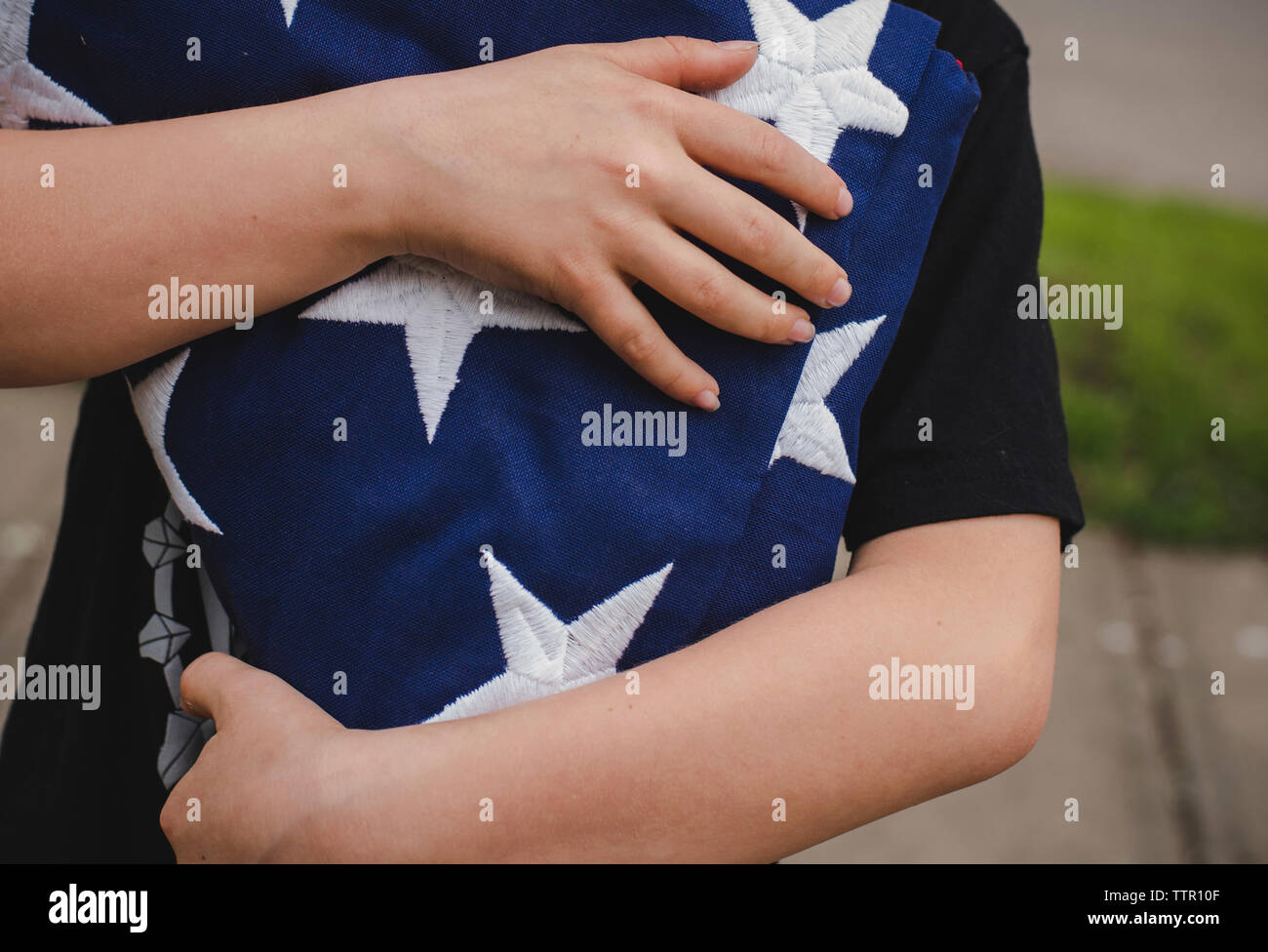 Mittelteil der boy Holding amerikanische Flagge beim Stehen im Hof Stockfoto