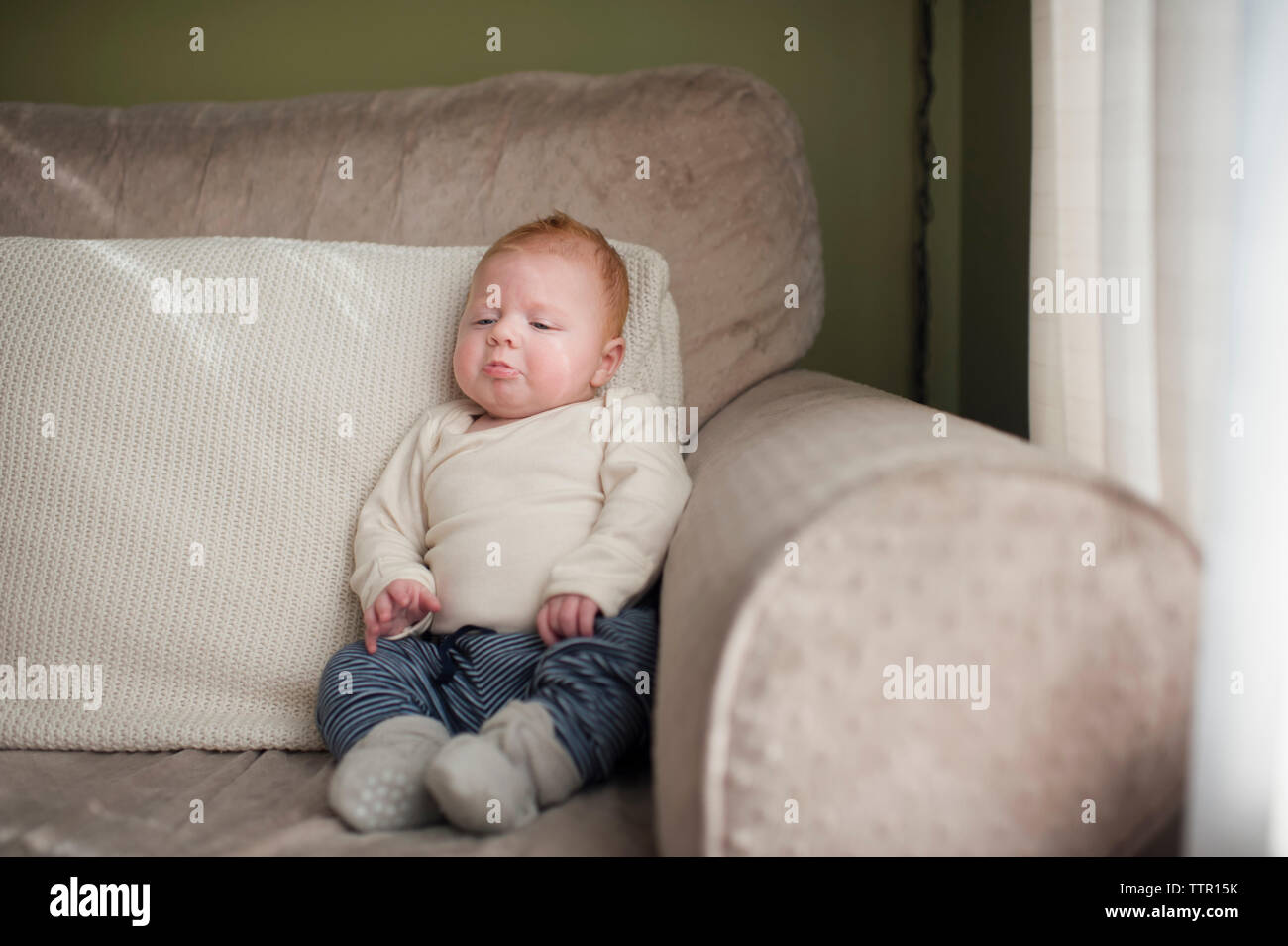 Cute Baby Junge runzelte die Stirn, während auf dem Sofa zu Hause sitzen Stockfoto