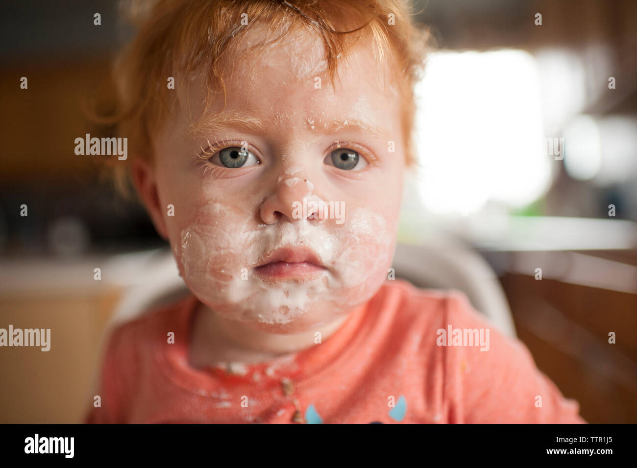 Close-up Portrait von cute baby boy mit unordentlichen Gesicht sitzen auf hohen Stuhl zu Hause Stockfoto